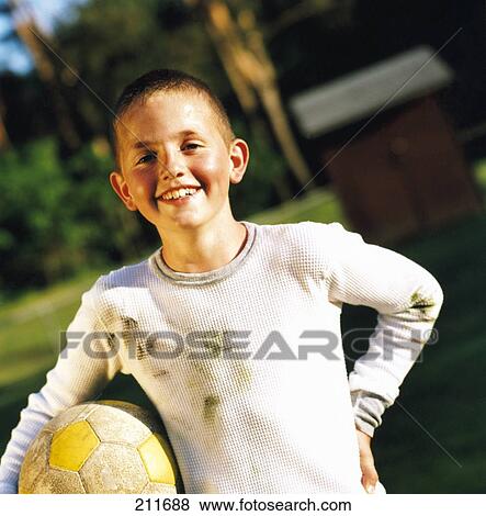 Stock Photo - Portrait of boy holding soccer ball and smiling . Fotosearch
