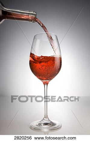 Stock Photograph - pouring red wine into a glass, close-up . Fotosearch