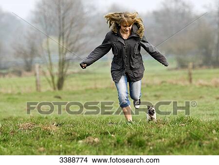 Pug puppy and teenage girl running over meadow View Large Photo Image Picture - Pug puppy and teenage girl running over meadow . Fotosearch