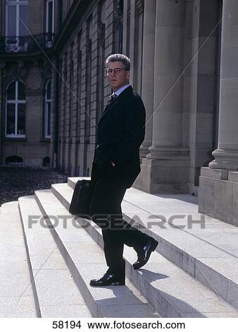 Picture - Side profile of businessman walking down stairs . Fotosearch