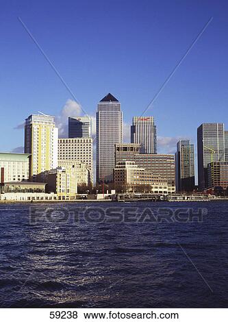 Stock Photo - Skyscrapers along river, Thames River, Canary Wharf, London, Europe . Fotosearch