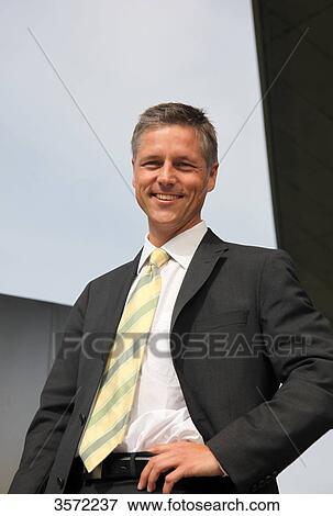 Stock Photo - Smiling businessman with hand on hip . Fotosearch