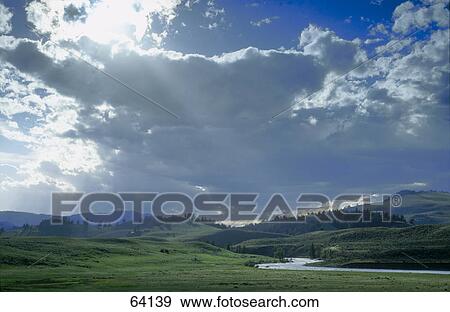 Stock Photo - Sunlight coming through clouds over landscape . Fotosearch