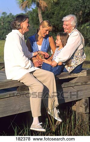 Three generation family sitting on wooden plank with friend View Large Photo Image Stock Photo - Three generation family sitting on wooden plank with friend . Fotosearch