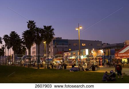 Stock Image - Tourists in front of lit up stores in market . Fotosearch