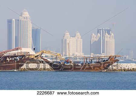 Stock Photo - Traditional boats Dhows in sea with skyscraper in background, Doha, Qatar . Fotosearch