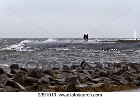 Two tourists during storm flood, at North Sea, Schleswig-Holstein, Germany View Large Photo Image Stock Image - Two tourists during storm flood, at North Sea, Schleswig-Holstein, Germany . Fotosearch