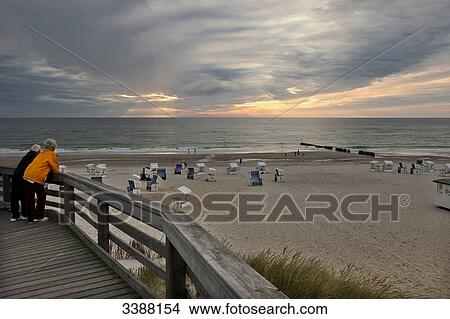 Two women on a wooden footbridge at the beach of Kampen, Sylt, Germany View Large Photo Image Picture - Two women on a wooden footbridge at the beach of Kampen, Sylt, Germany . Fotosearch