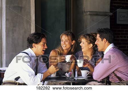 Stock Image - Two young couples talking to each other in cafe . Fotosearch