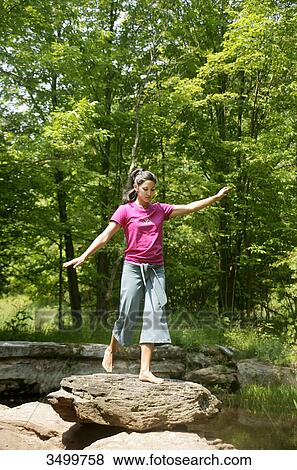 Stock Photo - Woman balancing on a rock, low angle view . Fotosearch