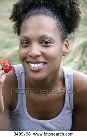 Stock Photo - Woman holding a strawberry, portrait . Fotosearch