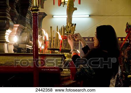 Woman lighting candle in Buddhist temple View Large Photo Image Stock Photo - Woman lighting candle in Buddhist temple . Fotosearch