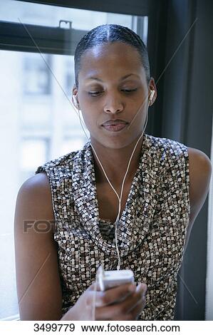 Woman looking at her MP3 player, low angle view View Large Photo Image Stock Photo - Woman looking at her MP3 player, low angle view . Fotosearch