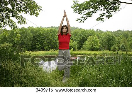 Woman practising yoga by a pond, front view View Large Photo Image Stock Photography - Woman practising yoga by a pond, front view . Fotosearch