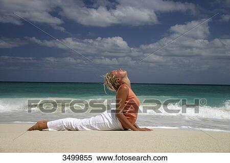 Woman practising yoga on a beach, side view View Large Photo Image Stock Photography - Woman practising yoga on a beach, side view . Fotosearch