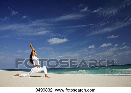 Stock Image - Woman practising yoga on a beach, Paradise Island, Bahamas, side view . Fotosearch