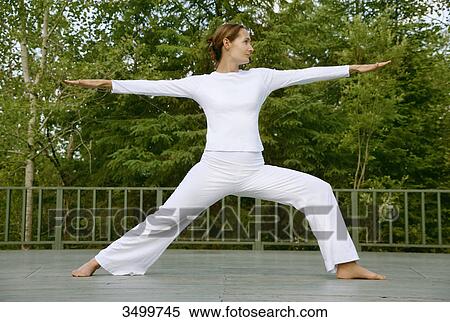 Stock Photography - Woman practising yoga on a deck, low angle view . Fotosearch