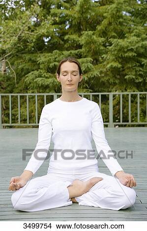 Picture - Woman sitting in lotus position on a deck, front view . Fotosearch