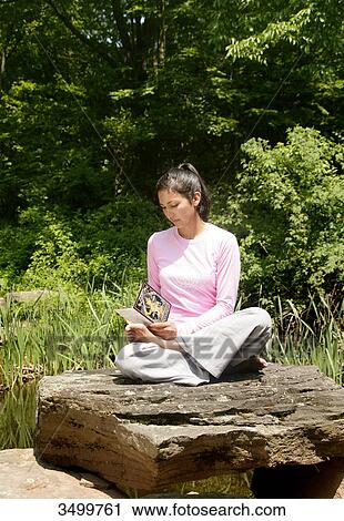 Woman sitting on a rock and reading a book View Large Photo Image Stock Image - Woman sitting on a rock and reading a book . Fotosearch