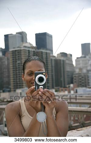 Woman taking picture with a camera, skyline of New York in the background, USA View Large Photo Image Stock Image - Woman taking picture with a camera, skyline of New York in the background, USA . Fotosearch