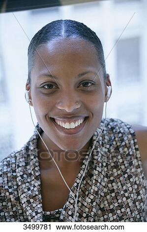 Stock Image - Woman with earphones smiling at camera, portrait . Fotosearch