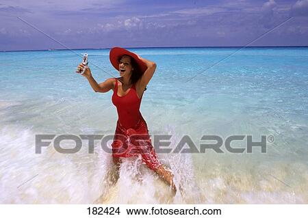 Woman with red skirt and hat standing at beach  View Large Photo Image Picture - Woman with red skirt and hat standing at beach . Fotosearch