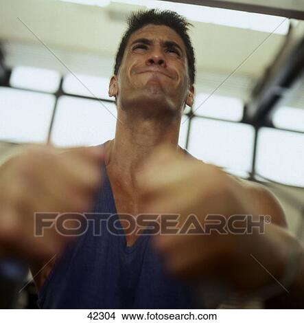 Young man exercising in a gym View Large Photo Image Picture - Young man exercising in a gym . Fotosearch