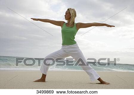 Young woman practising yoga on a beach, low angle view View Large Photo Image Stock Photo - Young woman practising yoga on a beach, low angle view . Fotosearch