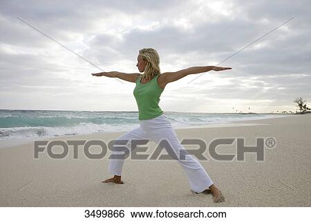 Young woman practising yoga on a beach, low angle view View Large Photo Image Stock Photograph - Young woman practising yoga on a beach, low angle view . Fotosearch
