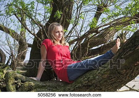 Stock Photograph - Young woman sitting at branch, portrait . Fotosearch