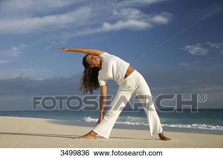 Stock Photograph - Young woman stretching at a beach, Paradise Island, Bahamas, low angle view . Fotosearch