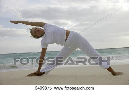 Young woman stretching on a beach, low angle view View Large Photo Image Stock Photography - Young woman stretching on a beach, low angle view . Fotosearch