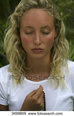 Young woman with closed eyes holding a necklace, portrait View Large Photo Image Stock Photo - Young woman with closed eyes holding a necklace, portrait . Fotosearch