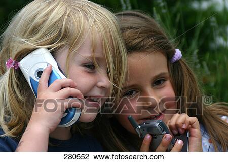Stock Image - Close-up of two girls with mobile phones . Fotosearch
