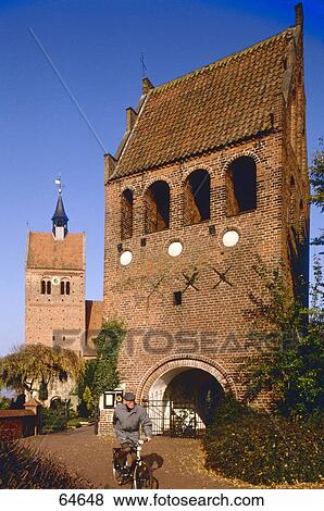 Stock Photo - Man cycling in front of church, St. Johannes Church, Bad Zwischenahn, Ammerland, Lower Saxony, Germany . Fotosearch