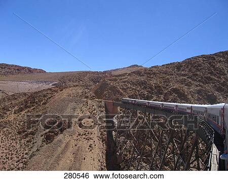 Stock Photograph - Passenger train passing through railway bridge, Argentina . Fotosearch