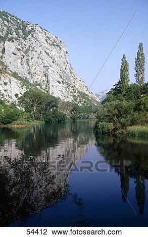 Stock Image - Reflection of mountain and sky in the river water, Cetina River, Omis, Croatia . Fotosearch