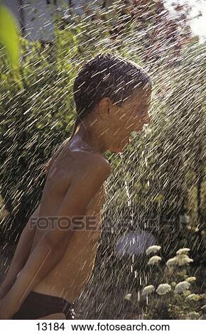 Picture - Side profile of boy playing under jet of water . Fotosearch