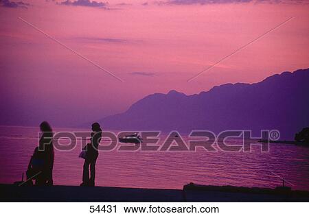 Silhouette of two people at the coast View Large Photo Image Stock Image - Silhouette of two people at the coast . Fotosearch