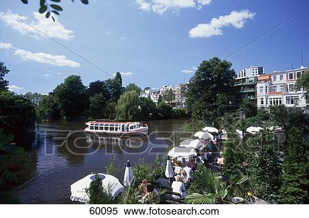 Stock Photography - Tourists sitting under sunshades at waterfront, Winterhude, Hamburg, Germany . Fotosearch