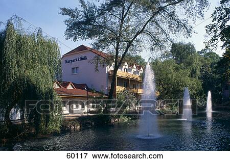 Stock Photo - Water fountain in pond in front of buildings, Eichsfeld, Lower Saxony, Germany . Fotosearch