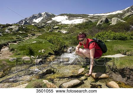 Stock Photography - Woman squatting at mountain brook, Monte Renoso, Corsica, France . Fotosearch