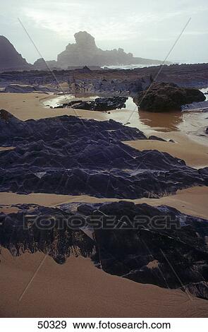 Stock Photo - Black rocks on beach, Atlantic Ocean, Algarve, Portugal . Fotosearch