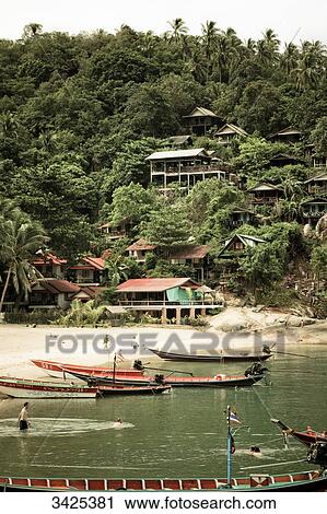 Stock Image - Boats and tourists on the beach of Ko Phangan, Thailand . Fotosearch