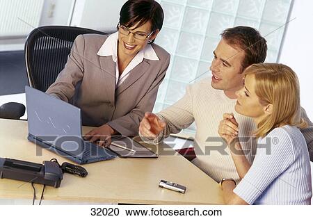 Businesswoman and a young couple looking at a laptop View Large Photo Image Stock Image - Businesswoman and a young couple looking at a laptop . Fotosearch