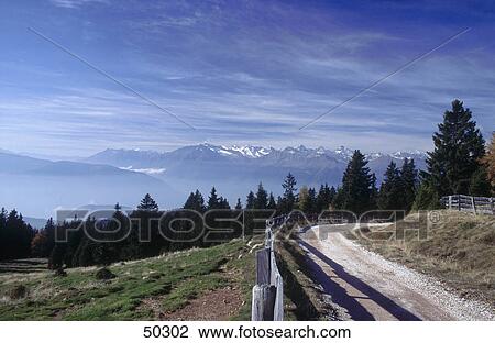 Stock Image - Fence along hiking trail with mountains in background, Dolomites, Etsch valley, Alto Adige, Italy . Fotosearch