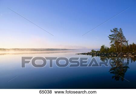 Stock Photo - Fog over lake at dawn, Langsjon Lake, Headmark County, Norway . Fotosearch