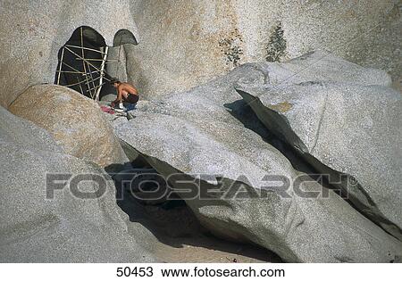 Stock Image - Man building housing cave, Sardinia, Italy . Fotosearch