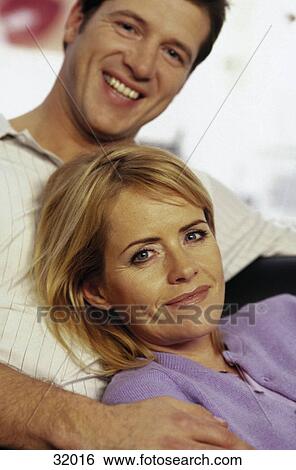 Stock Photograph - Portrait of a young couple smiling in a living room . Fotosearch