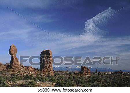 Stock Image - Rock formations on landscape with mountain range in distance, Balanced Rock, La Sal Mountains, Arches National Park, Utah, USA . Fotosearch